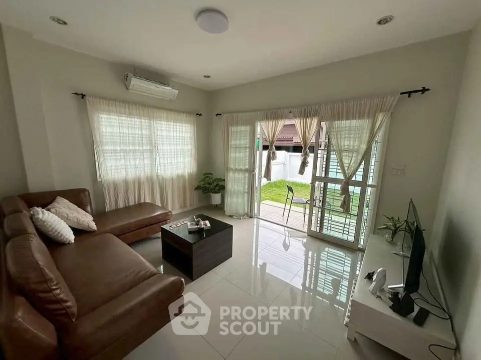 Spacious living room with leather sofa and garden view, perfect for relaxation.