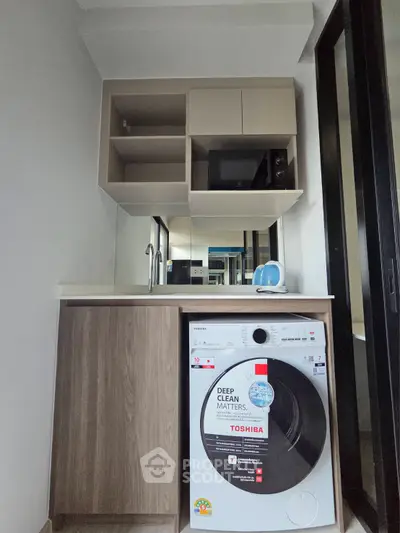 Modern compact kitchen with washing machine and microwave in sleek design.