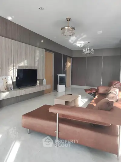 Spacious modern living room with elegant brown leather sofa and stylish decor.