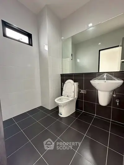 Modern bathroom with sleek black and white tiles and contemporary fixtures.