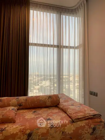 Cozy bedroom with floral bedding and large window offering a city view.