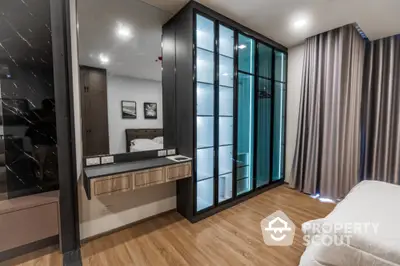 Modern bedroom with sleek glass wardrobe and elegant wood flooring