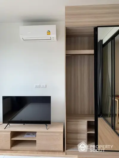 Modern living room with sleek TV stand and built-in wardrobe, featuring air conditioning for comfort.