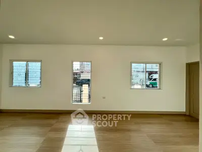Spacious unfurnished room with wooden flooring and large windows for natural light.