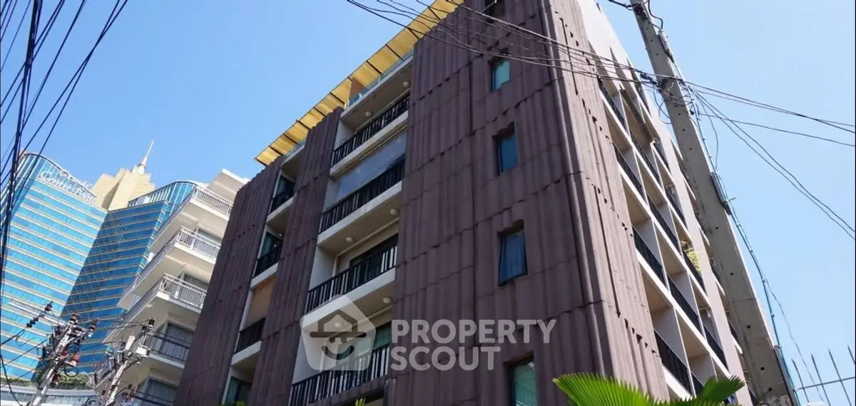 Modern multi-story building with balconies in urban setting, showcasing contemporary architecture.