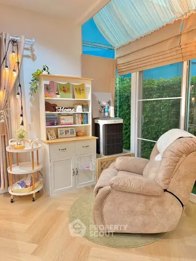 Cozy living room with plush recliner, bookshelf, and large window overlooking greenery.