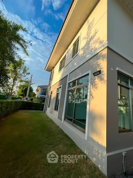 Modern two-story house with large windows and lush green lawn, perfect for family living.