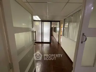 Spacious office corridor with wooden flooring and glass partitions