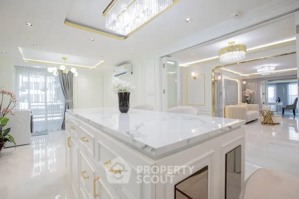 Luxurious open-plan living room with elegant marble island and modern lighting fixtures.