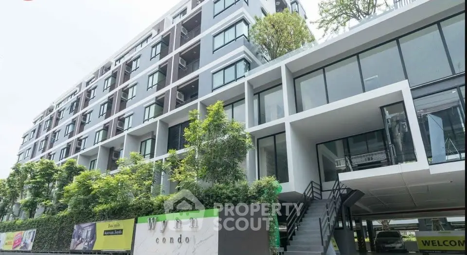 Modern condominium building with lush greenery and sleek architectural design.