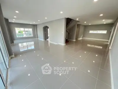 Spacious modern living room with glossy tile flooring and ample natural light.