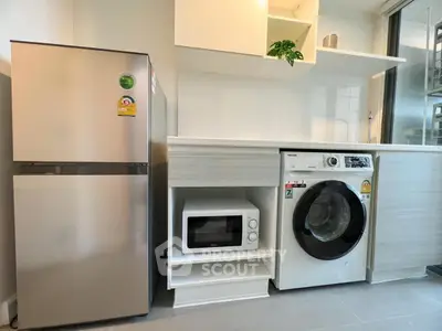 Modern kitchen with stainless steel fridge, washing machine, and microwave in sleek design.