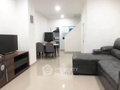 Modern living room with sleek furniture and open layout leading to kitchen.