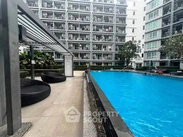 Modern apartment complex with a spacious outdoor pool and stylish seating area, perfect for relaxation.