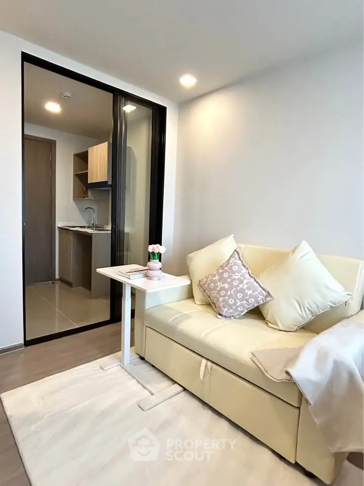 Modern living room with cozy sofa and open kitchen layout in a stylish apartment.