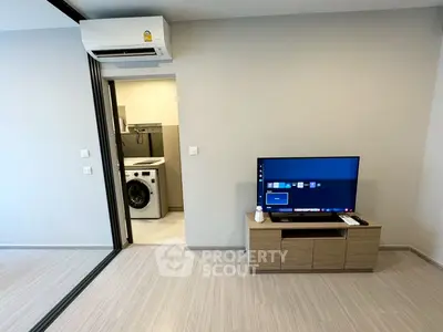 Modern living room with TV and washing machine in sleek apartment.