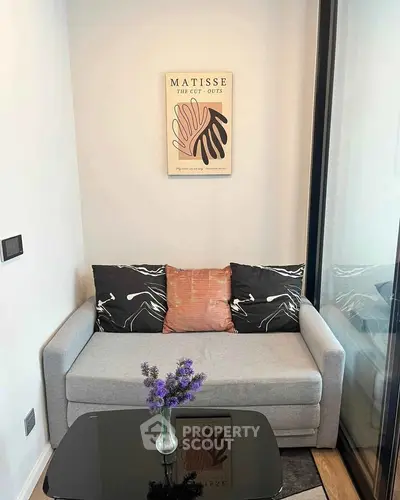 Cozy living room with modern decor and stylish artwork, featuring a comfortable sofa and elegant glass table.