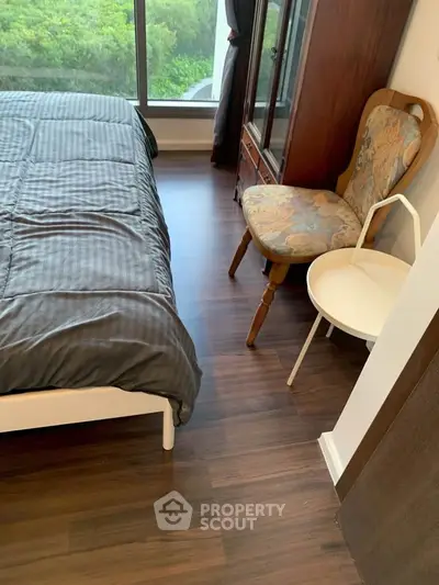 Cozy bedroom with elegant wooden flooring and large window view.