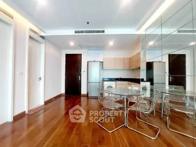 Modern open-layout kitchen with sleek appliances and mirrored wall in stylish apartment.