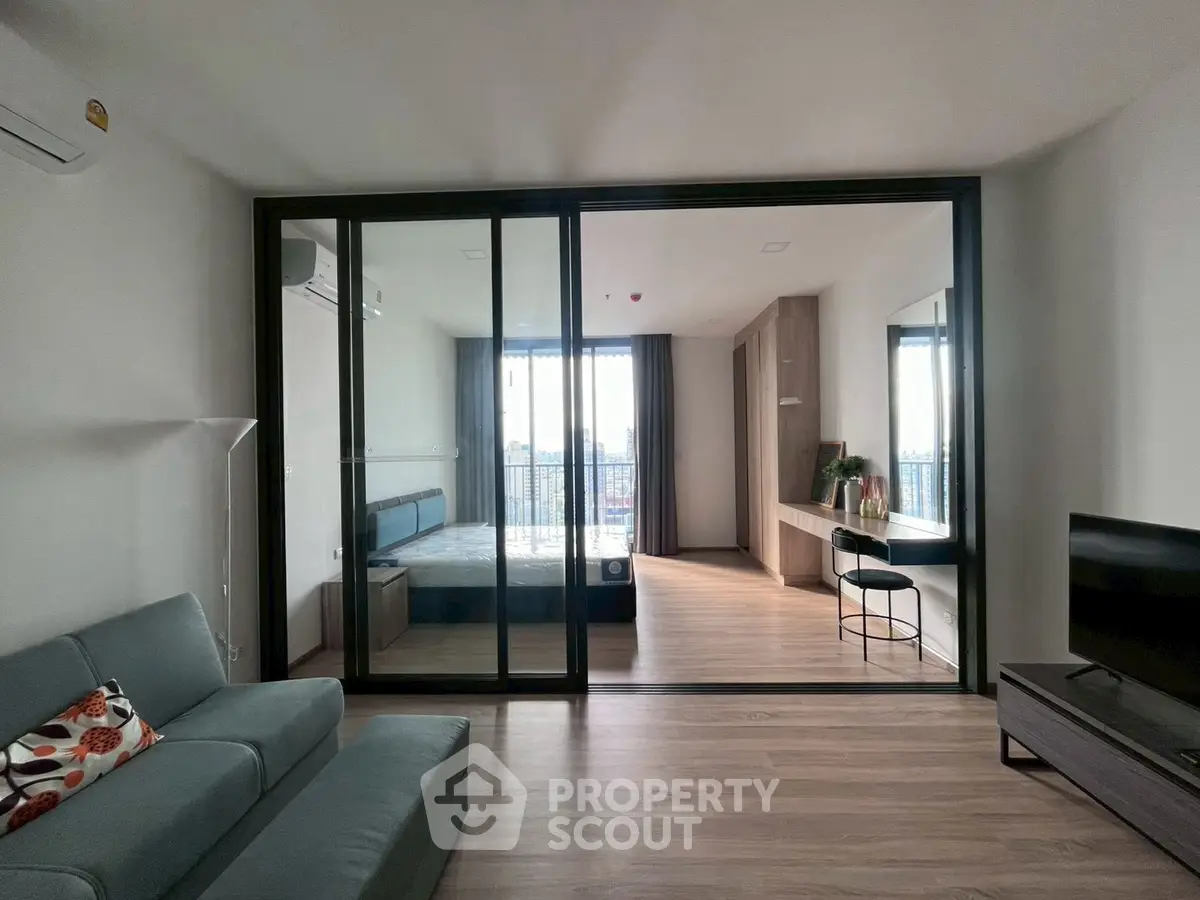 Modern studio apartment with glass partition, cozy living area, and city view balcony.