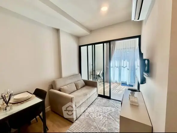 Modern living room with cozy sofa and glass partition leading to balcony