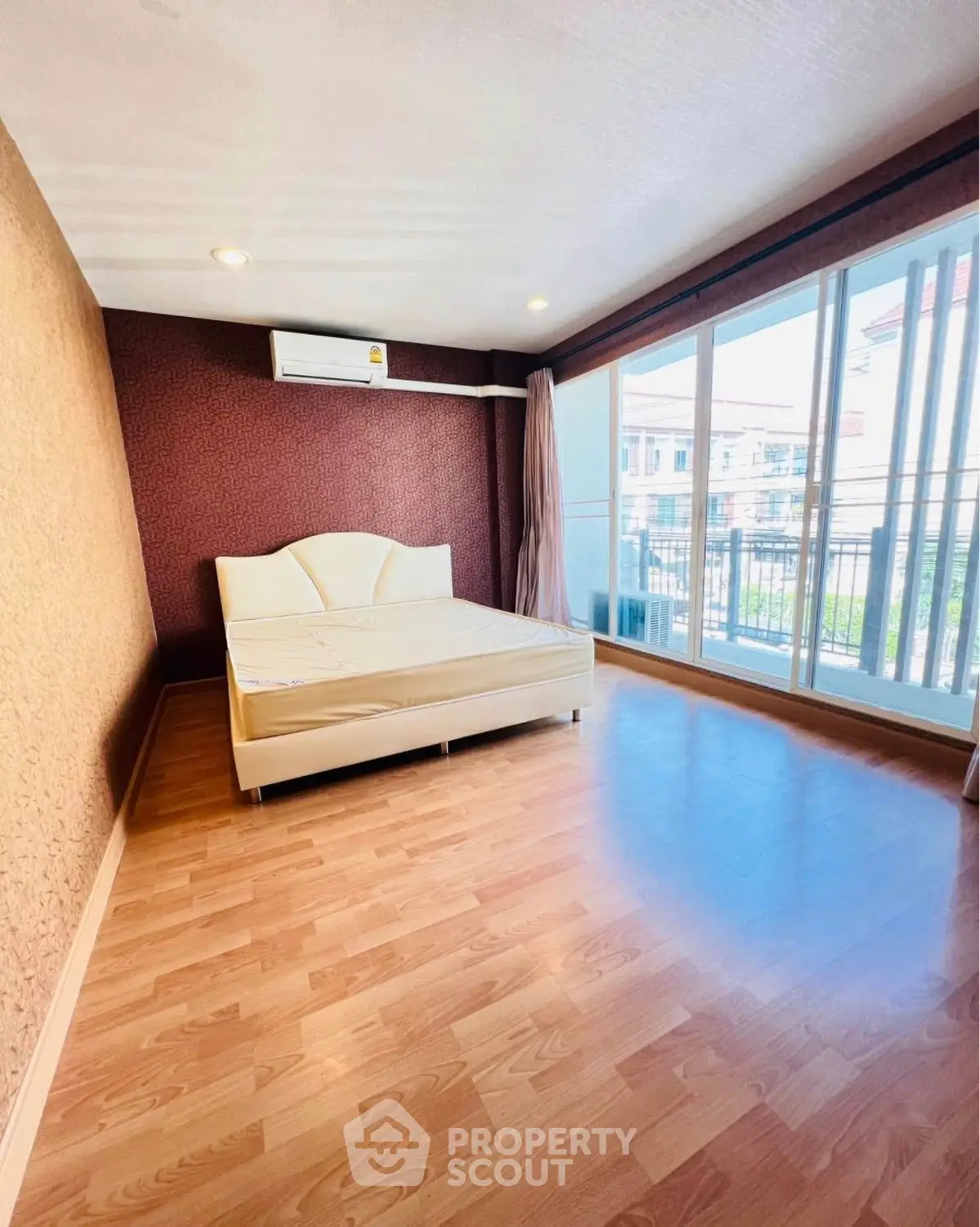 Spacious bedroom with large windows and wooden flooring in modern apartment