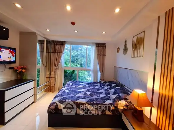 Cozy bedroom with large window and modern decor, offering a serene view of greenery.