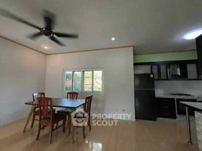 Modern dining area with ceiling fan and adjacent kitchen in open layout