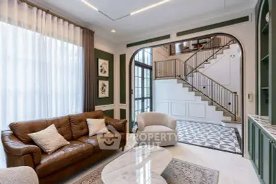 Elegant living room with leather sofa, stylish armchairs, and a grand staircase in a luxurious home.
