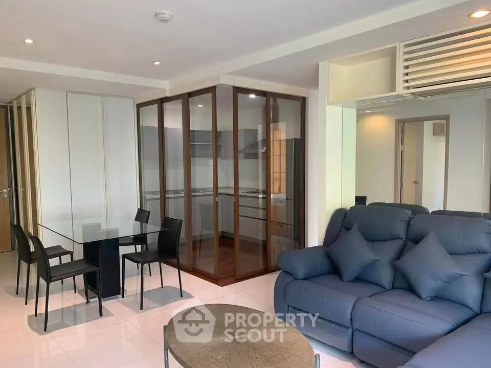 Modern living room with glass-enclosed kitchen and stylish furniture in a contemporary apartment.