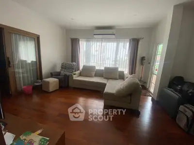 Spacious living room with large windows and wooden flooring, perfect for relaxation and entertainment.