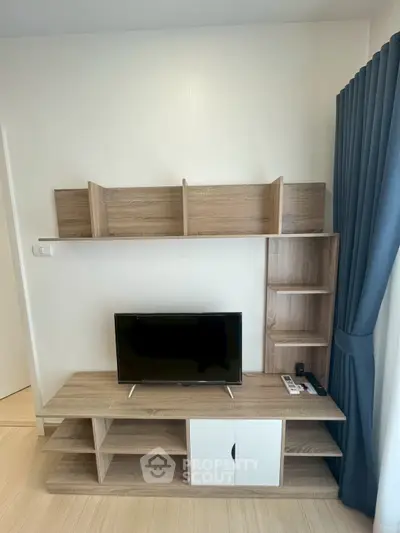 Modern living room with stylish wooden TV stand and shelving unit, complemented by elegant blue curtains.