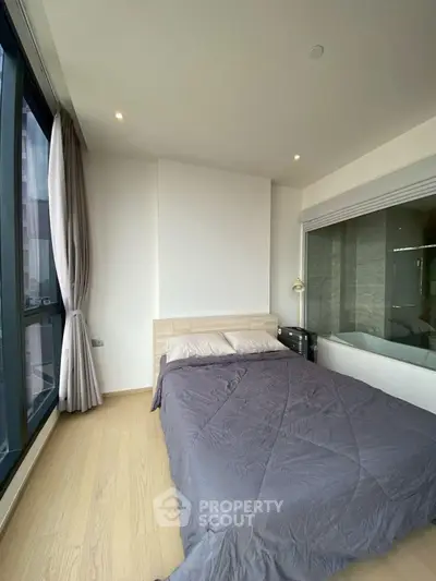 Modern bedroom with large window and bathtub view, featuring sleek design and natural light.