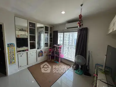 Spacious living room with large window and built-in storage in modern apartment.