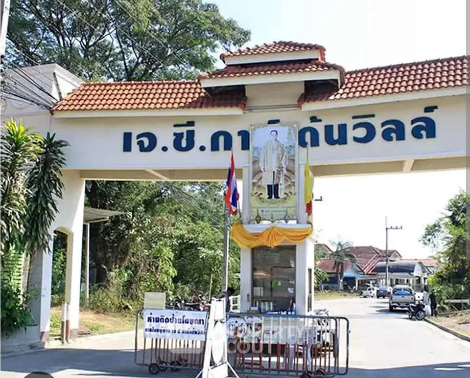 Charming gated entrance of residential community with traditional architecture and lush greenery.