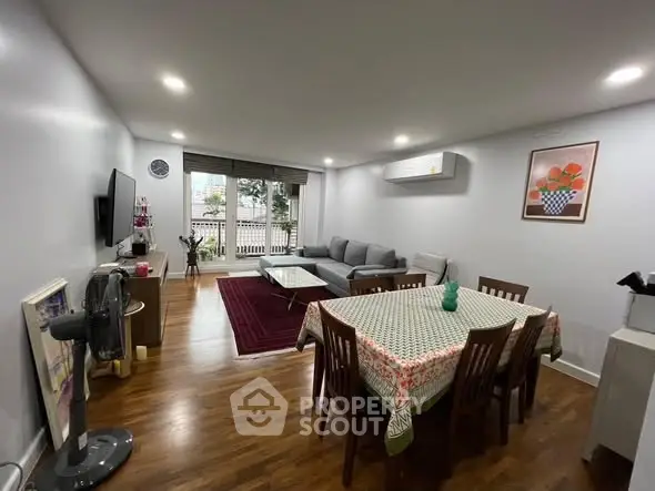 Spacious living room with modern decor and dining area, featuring hardwood floors and ample natural light.