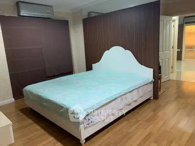 Spacious bedroom with elegant wooden flooring and modern air conditioning unit.