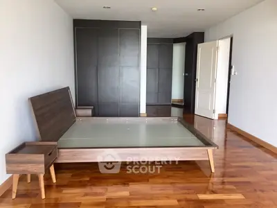 Spacious bedroom with modern wooden flooring and sleek furniture design.