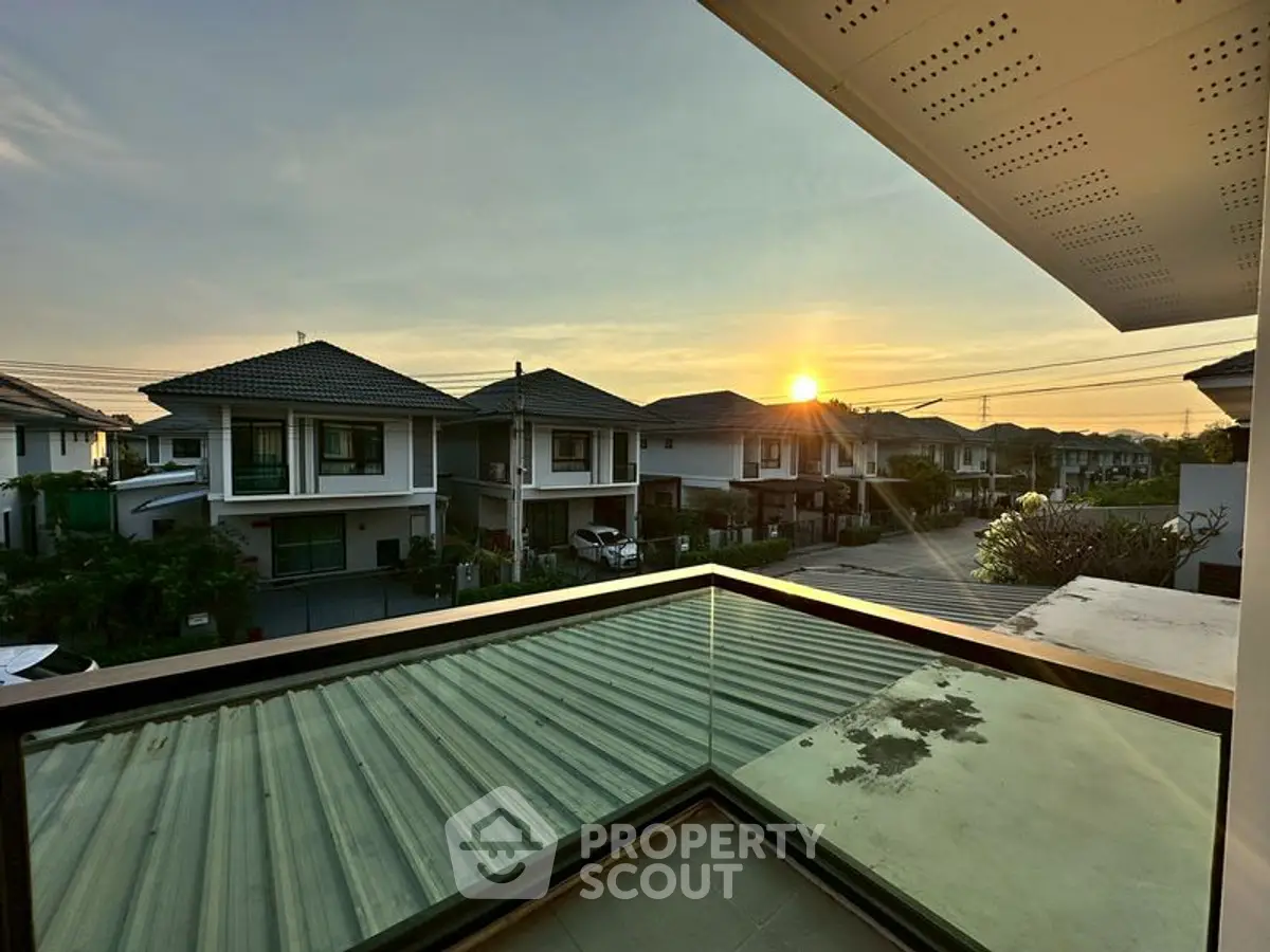 Stunning sunset view from a modern balcony overlooking a serene neighborhood.