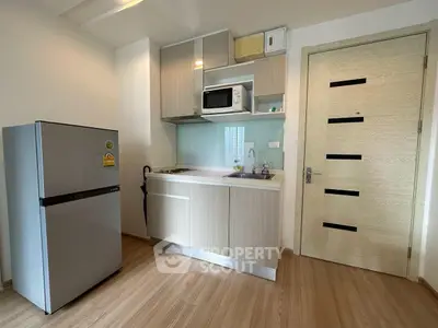 Modern kitchen with sleek cabinetry and stainless steel fridge in a compact apartment.