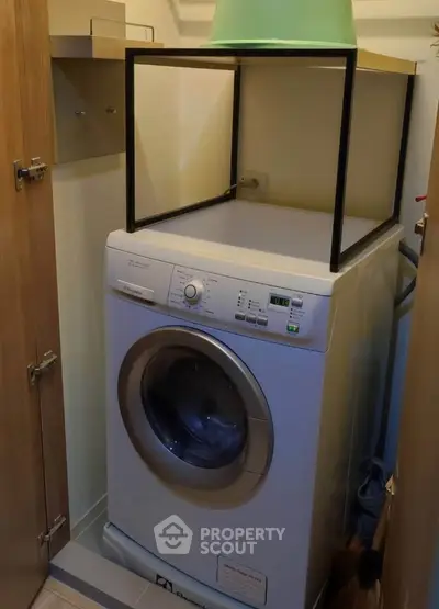 Compact laundry area with washing machine in a cozy storage space.