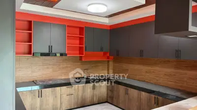 Modern kitchen with sleek cabinetry and vibrant red accents, featuring a spacious countertop and stylish lighting.