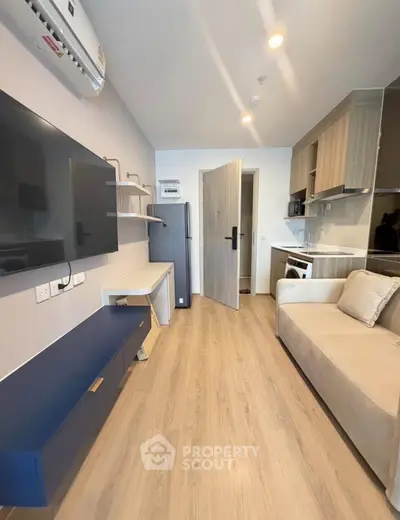 Modern living room with sleek furniture and integrated kitchen appliances in a compact apartment.