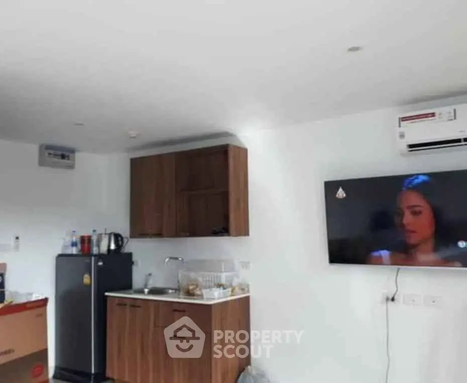 Modern kitchen with compact layout and wall-mounted TV in cozy apartment.