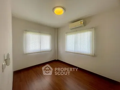 Spacious bedroom with wooden flooring and air conditioning, perfect for comfort and relaxation.