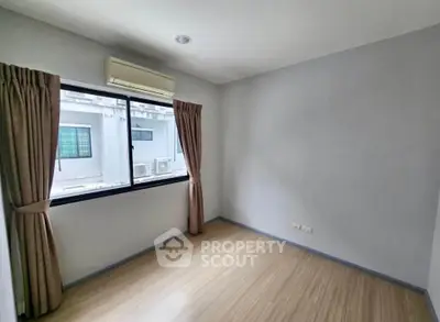 Spacious empty room with large window and air conditioning unit.