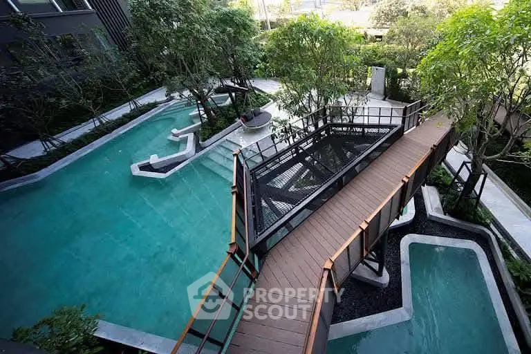 Luxurious outdoor pool area with modern bridge and lush greenery, perfect for relaxation and leisure.