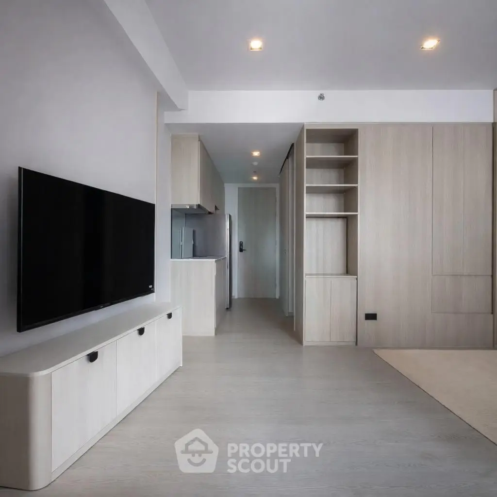 Modern minimalist living room with sleek TV unit and open kitchen layout