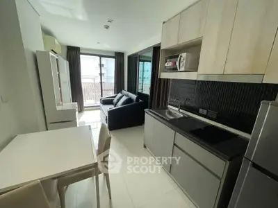 Modern apartment with open kitchen and cozy living area, featuring sleek cabinetry and natural light.