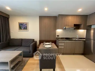 Modern open-layout living room with kitchen, featuring sleek furniture and stylish decor.